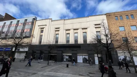 The old Marks and Spencer site with boarded up windows and no signage. 