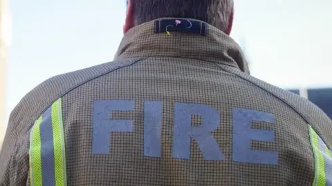 PA Media A generic image of the back of a firefighter, with FIRE written on his jacket