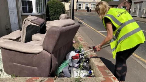 BBC Tony Preston, one of the Wombles in Spalding, is dressed in a high visibility jacket and is seeing picking litter beside a couple of dumped sofas