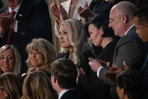 Getty Images A tearful Erika Kirk surrounded by other guests of Donald Trump's State of the Union address, who are applauding
