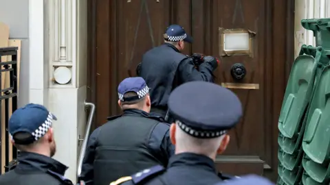 Reuters Officers use a battering ram to break down a door