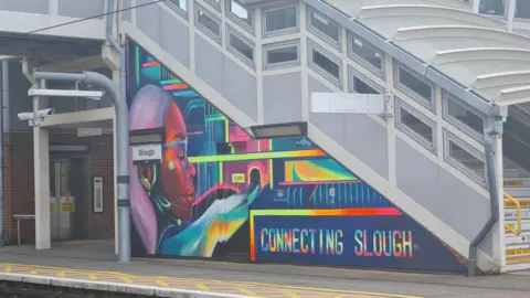 A mural of a girl in multiple colours. Next to her are the words "Connecting Slough".