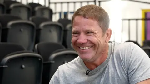 Steve Backshall is pictured smiling and wearing a light coloured T shirt