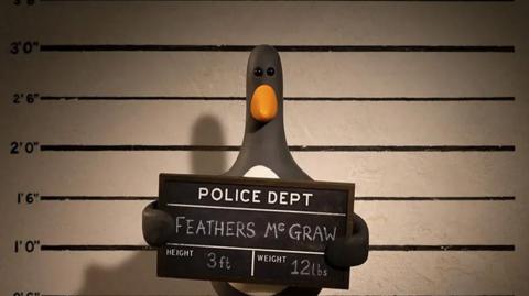 feathers mcgraw the penguin at a police booking station measuring 3 feet tall