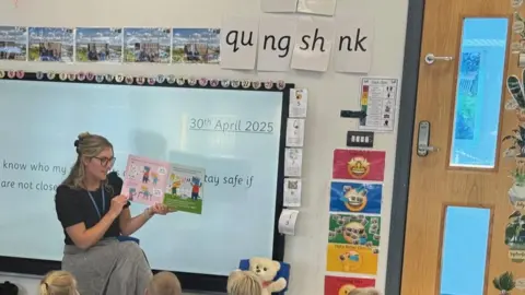 BBC Reception class teacher showing children pictures from the Pantosaurus book.