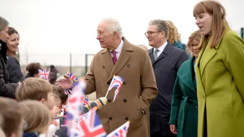 PA Media The King, Prime Minister and Deputy Prime Minister on a visit together in Cornwall - children are waving Union flags and the trio are smiling and speaking with the crowd