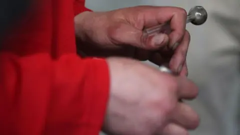 Getty Images A man's hands are seen holding a crack pipe