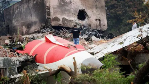 A fire officer stands next to the tail section of the crashed Air India Boeing 787-8 Dreamliner aircraft, in Ahmedabad, India.