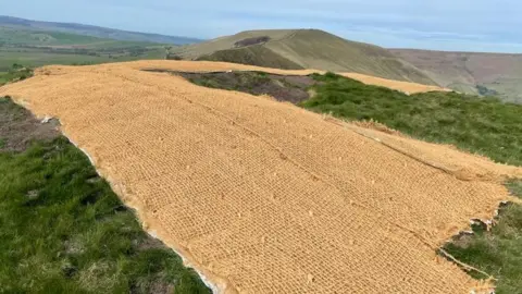 BBC A hillside covered with beige hessian sheeting