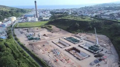 Manx Utilities A aerial view of the site of the construction of the new sewage works, with the town of Peel along with the power station tower in the distance.