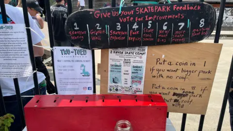 Angel Joseph/BBC é usado como um sinal de um skate que diz em Red Writing: 'Vote para a melhoria do seu feedback de skatepark' com as oito coisas pelas quais as pessoas votam. Abaixo está uma caixa vermelha onde as pessoas podem colocar uma moeda no slot que as pessoas optam por votar.
