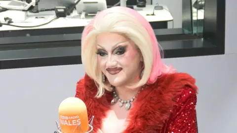 Catrin Feelings in the Radio Wales studio. She sits behind an orange mic.