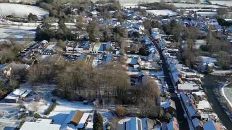 Stuart Howells/BBC An aerial view of homes, fields and trees in Nayland, in Suffolk, which are covered in snow.