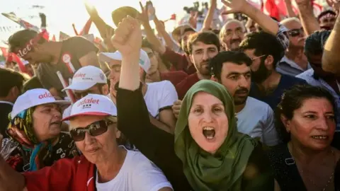 AFP People cheer as Turkey's main opposition CHP leader Kemal Kilicdaroglu throws flowers to supporters during a rally in Istanbul (09 July 2017)