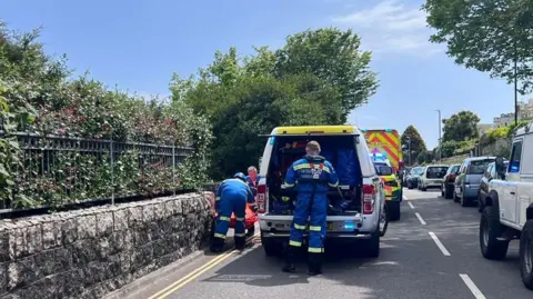 Two emergency service workers opening the back of an emergency service vehicle. 