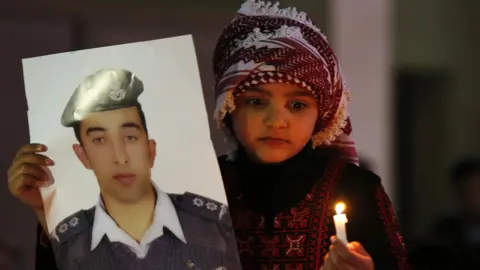 A Jordanian girl holds a poster of pilot Muath al-Kasaesbeh
