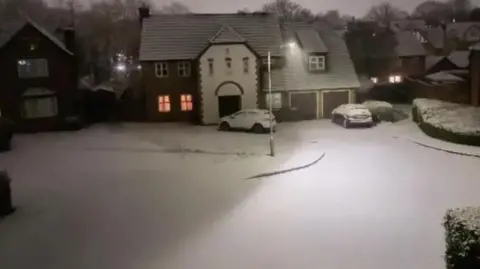 BBC Weather Watchers/Julian A snowy scene with a house and cars with a dusting of snow at night