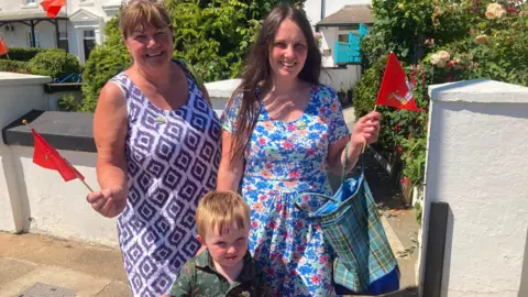 Sue and her daughter and grandson waving Manx flags.