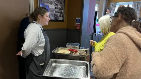 Becki Thomas/BBC Tina queuing for a hot meal at Rayners pub in Hull