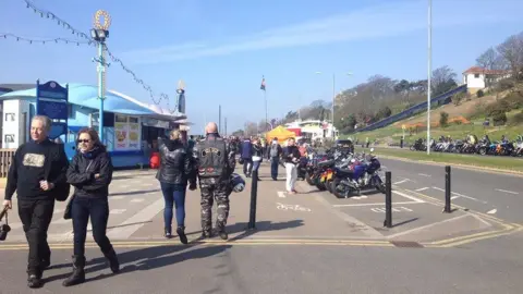 Nick Hull/BBC People walking along Southend seafront with motorcycles also in the image