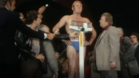 BBC Richard Dunn standing on weighing scales