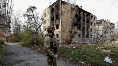 RL/SERHII NUZHNENKO/Reuters A Ukrainian soldier looks at destroyed buildings in Avdiivka, eastern Ukraine. File photo