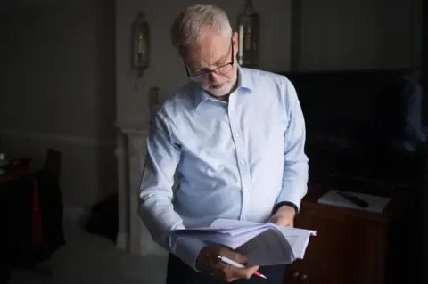 Stefan Rousseau/ PA Jeremy Corbyn reads from a notebook.
