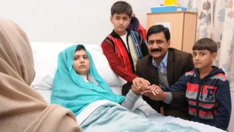 University Hospitals Birmingham Malala in hospital bed surrounded by her family