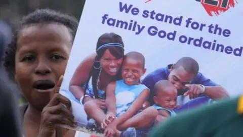 Getty Images Members of the Christian community seen holding placards in celebration after Kenyas High Court ruled to uphold the British-era penal code that criminalises gay sex (2019)