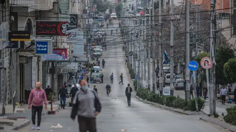 EPA Palestinians walk down a street in Gaza City in April before the recent fighting broke out