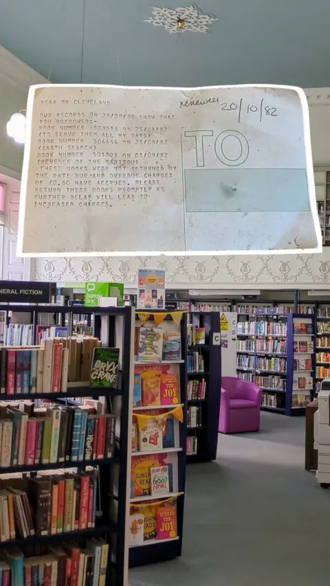 A library with multiple bookshelves with a highlighted piece of paper above