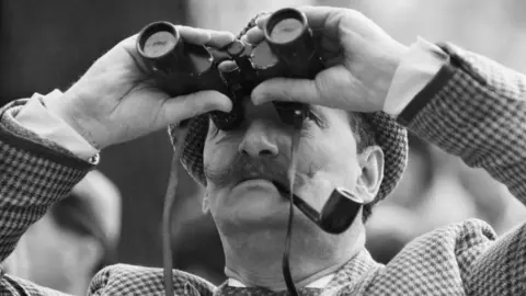 Getty Images Man looks at sky with binoculars