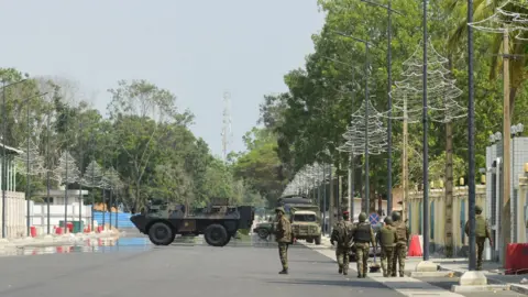 Reuters Armoured vehicles and soldiers seen on main road in Cotonou, Benin with Christmas tree lights hung on lamp posts - 7 December 2025.