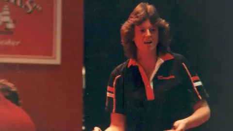 Dr Linda Duffy Dr Linda Duffy di turnamen dart pada tahun 1984, mengenakan kemeja polo berwarna gelap