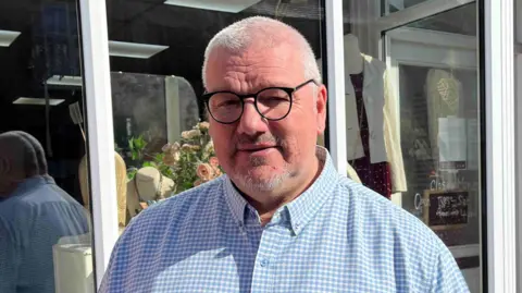 BBC Steve Payne in black rimmed glasses and a blue checked shirt