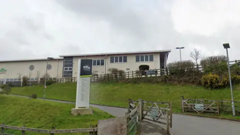 Truro and Penwith College with a sign outside on a bank of grass leading up to the college building.