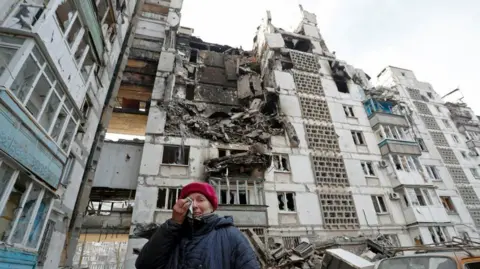 Reuters Valentina Demura, 70, reacts next to the building where her apartment, destroyed during Ukraine-Russia conflict, is located in the besieged southern port city of Mariupol, Ukraine March 27, 2022.