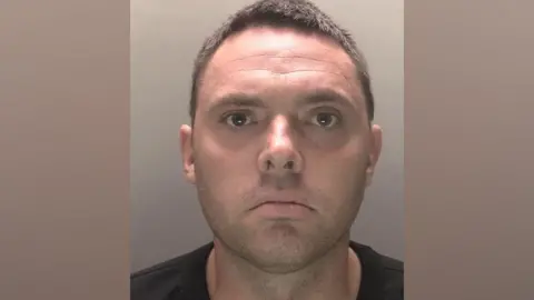 PA Media Christopher Beard stares straight at the camera in his police mugshot