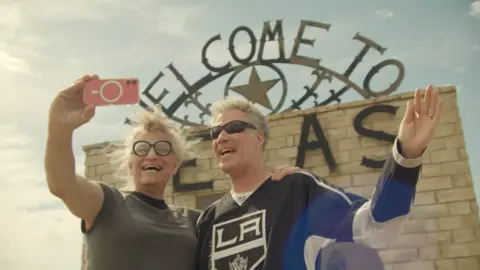 Netflix Harper Steele, wearing dark glasses with her hair swept back, poses with Will Ferrell, who has short gray hair and dark glasses