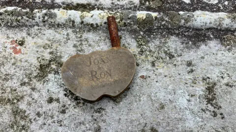 A rusting padlock sits on the railing of Gower Bridge in Llanrwst. The name's Joan and Ron are displayed on it with the date November 1959.