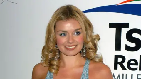 Getty Images Katherine Jenkins photographed wearing a blue dress with curly blonde hair before a tsunami relief concert in 2005