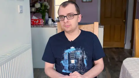 A man in a blue t shirt with glasses
