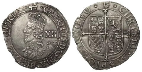 Essex Coin Auctions A front and back image of a Charles I silver shilling, worn at the edges but with clear markings. His profile is on the front with the letters XII and on the back is a coat of arms.