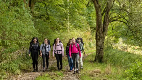 The Duke of Edinburgh's Award / Bob Martin Six teenage girls walking outside with backpacks on 