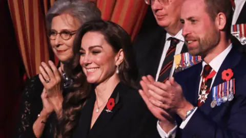 Catherine, Princess of Wales, smiles standing next to the Prince of Wales at a Remembrance concert in London on 9/11