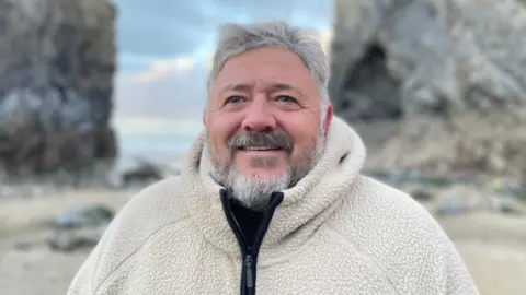 A man with a white beard wearing a white fleece