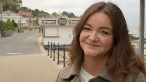 Jamie Niblock/BBC A head and shoulders image of Jenny Riddell-Carpenter, who is standing on a promenade. She is smiling and looking into the camera.