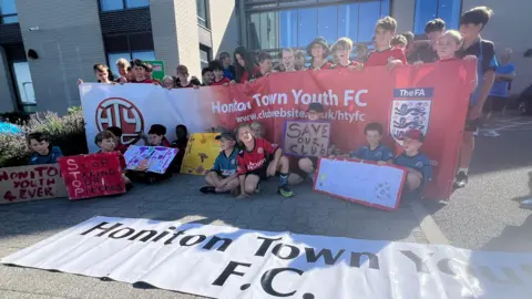 Children sat protesting. They are holding banners and painted signs.
