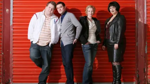 Baby Cow Productions/Neil Bennett/PA Four actors from the sitcom Gavin and Stacey are stood in front of a red shutter, which is pulled down.