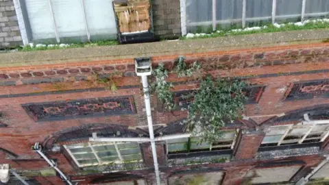 Stoke-on-Trent City Council / Arcadis An aerial view of a red brick building with numerous broken window panes and vegetation growing up parts of the building.